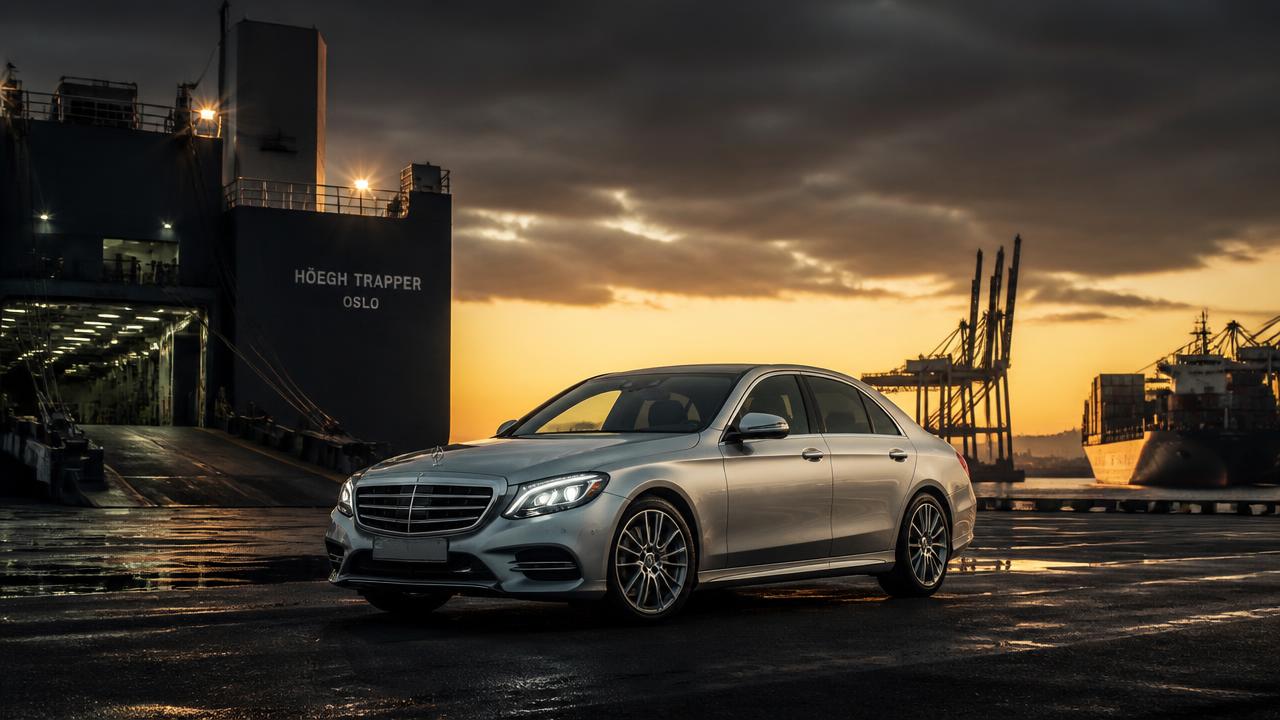 European luxury sedan at a United States vehicle export facility at dusk
